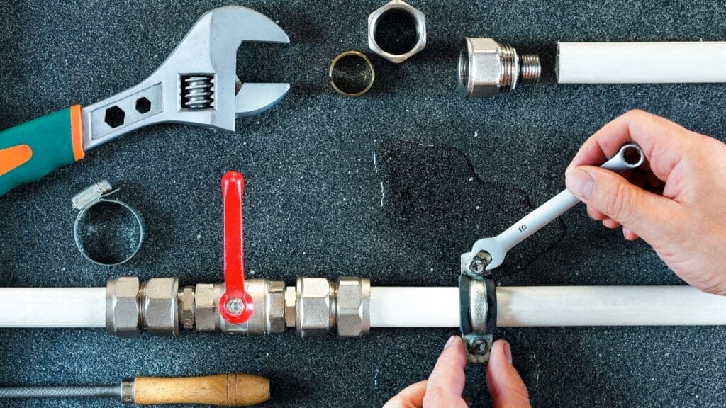 Plumber repairing a pipe valve with an adjustable wrench in Deltona