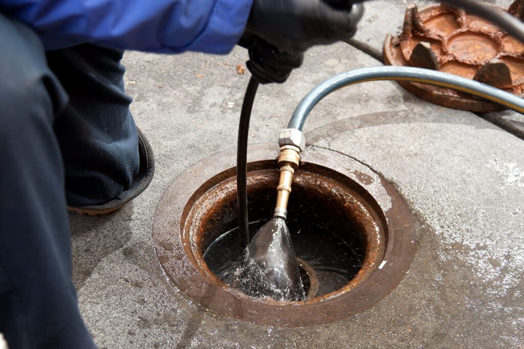 Plumber hydro jetting a sewer line through a manhole in Deltona