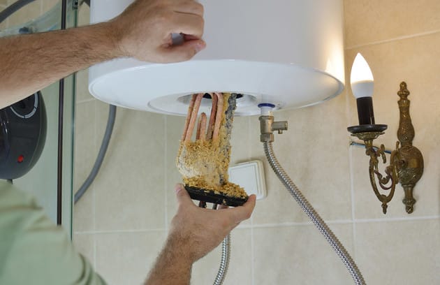 Technician removing mineral buildup from a water heater in Deltona